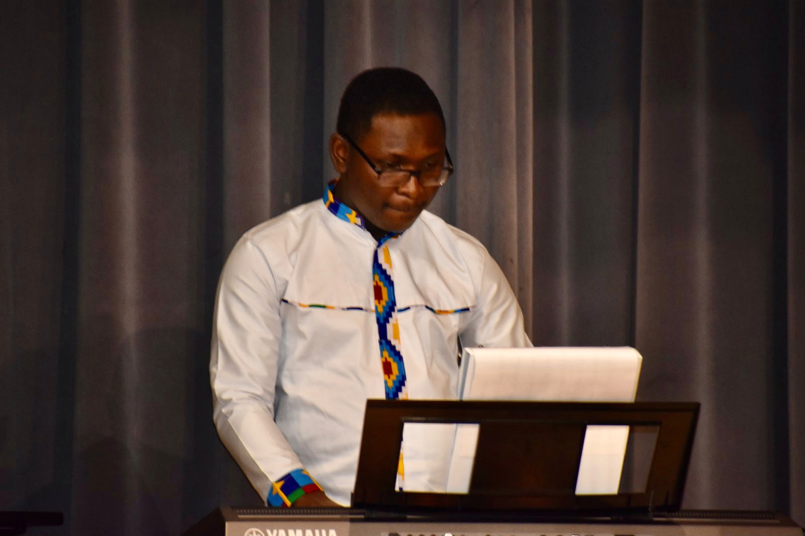 Dr. Nathanael Adjei playing keyboard in kente