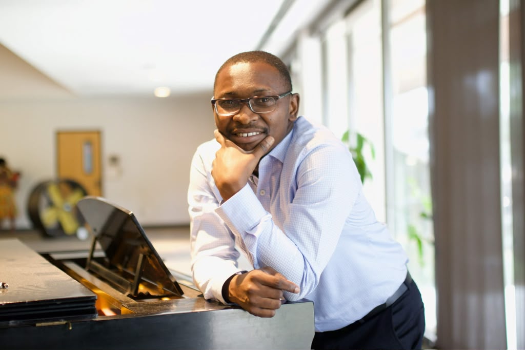 Dr. Nathanael Adjei resting on a piano